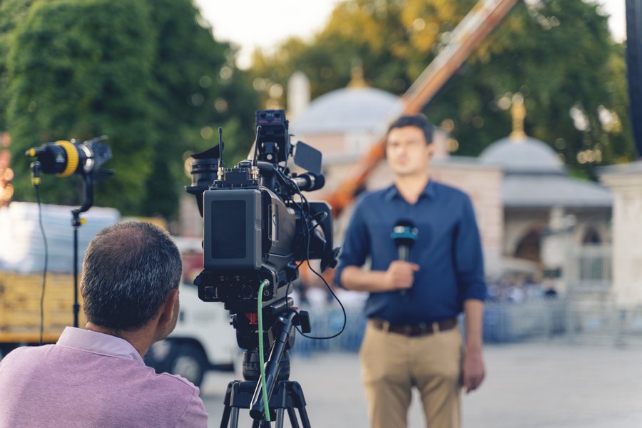 outdoor-live-report.jpg Camera crew filming a reporter during a live broadcast outdoors in front of a historic building.