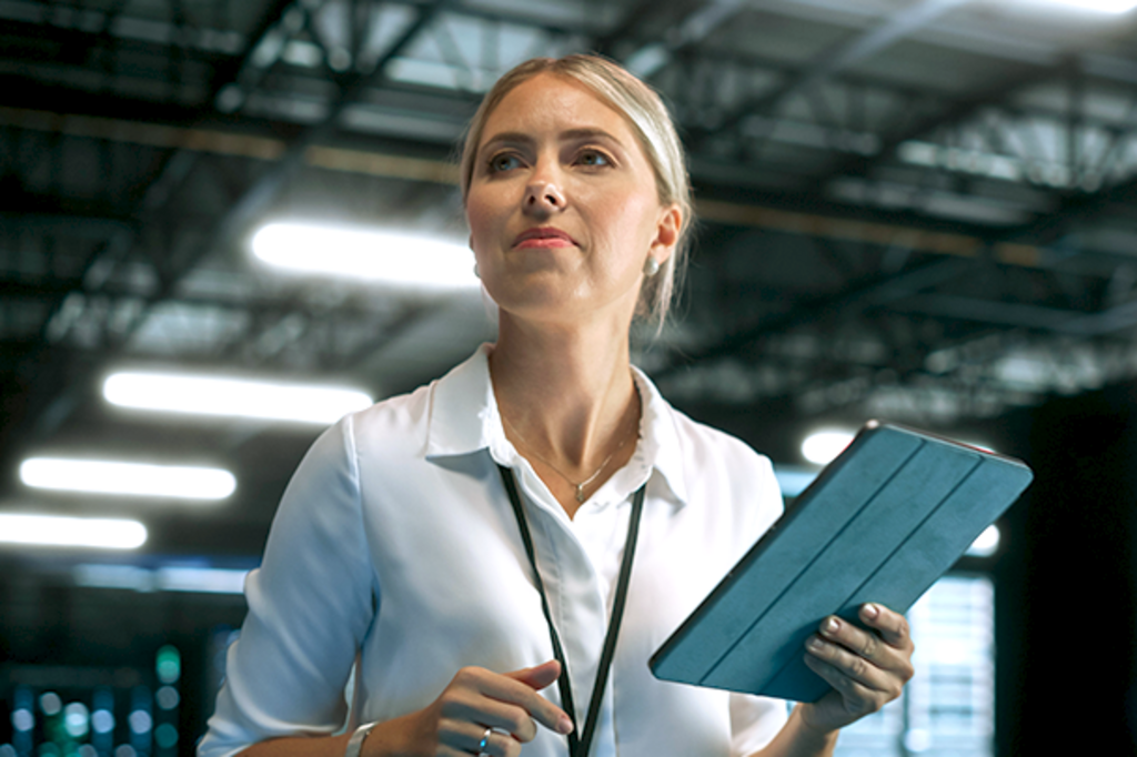 Woman holding a tablet and looking focused in a modern industrial or technology environment.