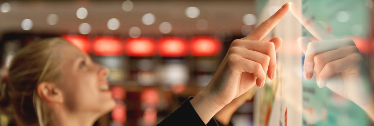 Woman using an interactive touchscreen in a modern retail environment.